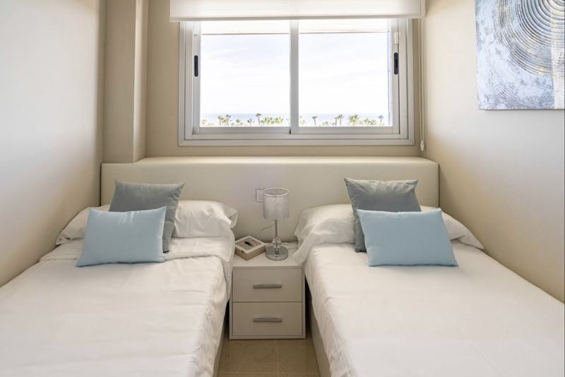Dormitorio con dos camas y ventana con vistas al mar