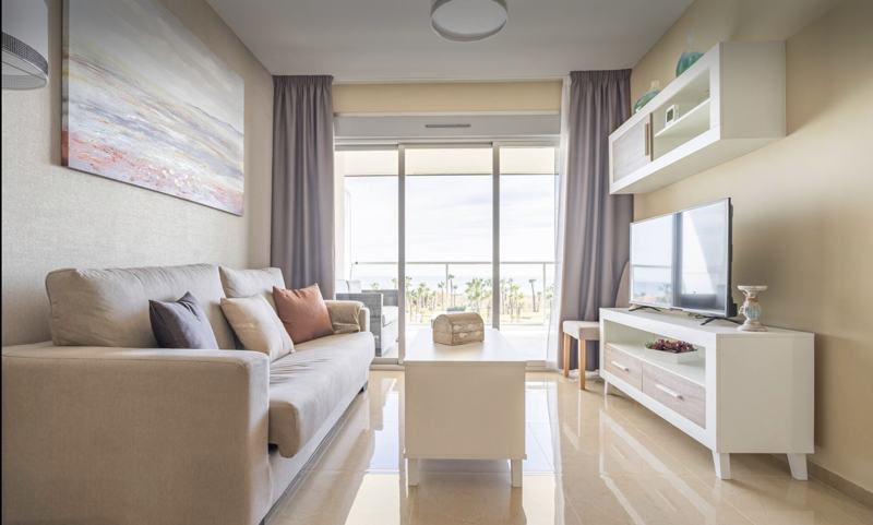 Salón con sofá y ventanal a la terraza con vistas al mar